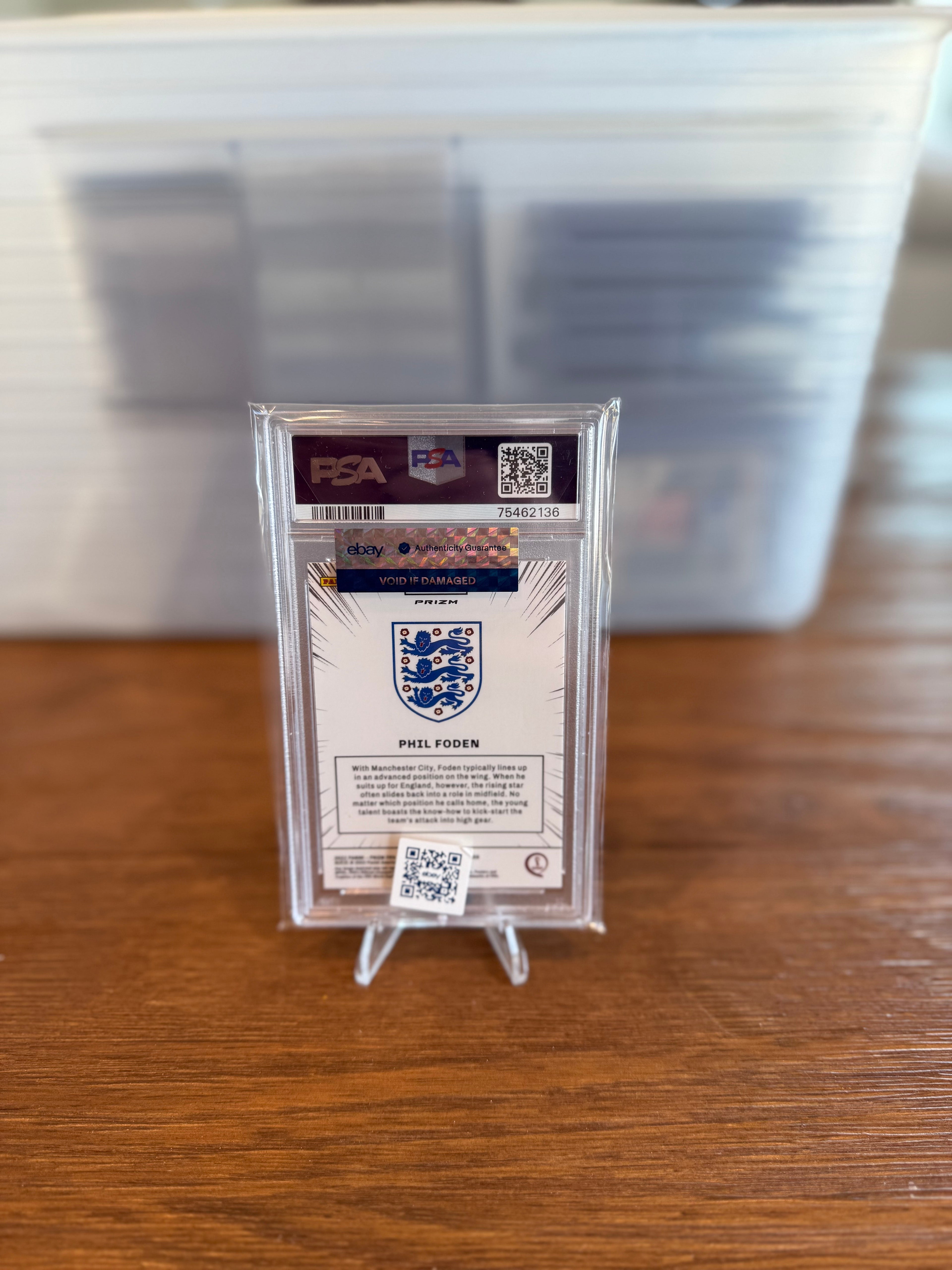 Trading card in a clear holder with a PSA logo on a wooden surface
